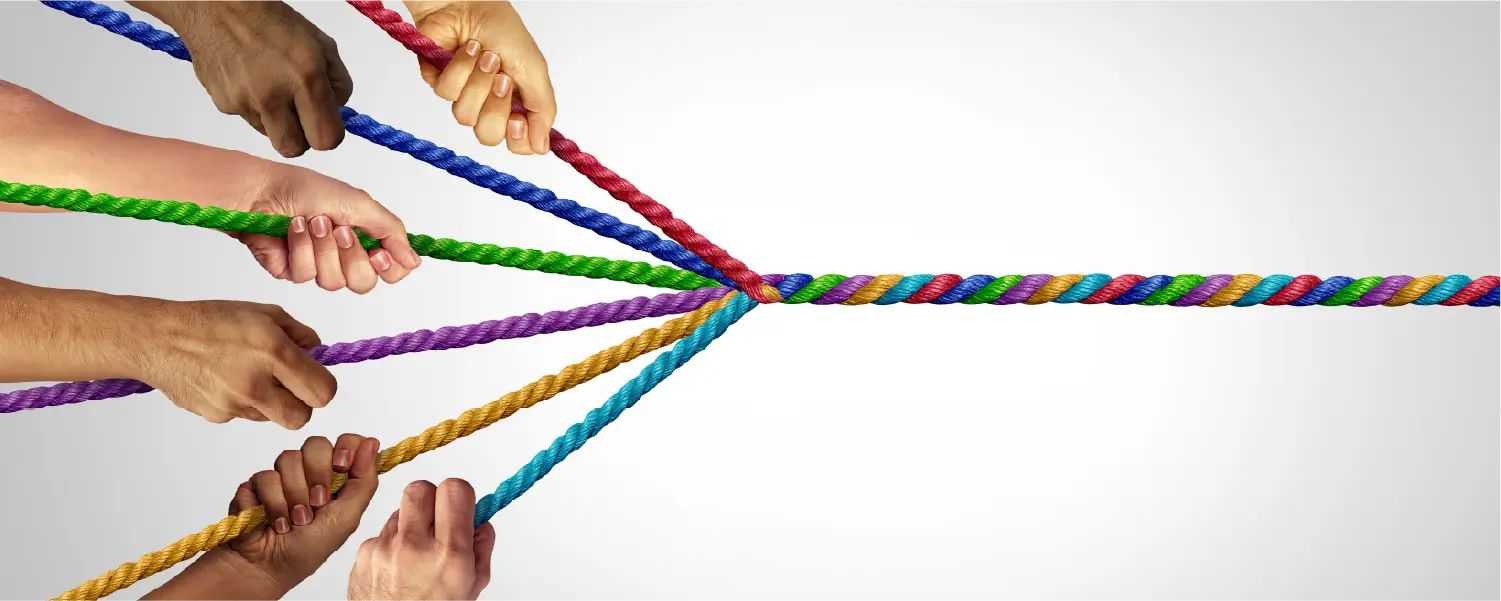 Several hands holding a colorful rope, featuring a mix of bright colors woven together.